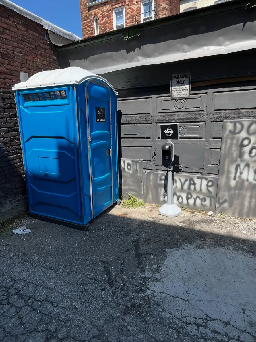 Blue porta potty on asphalt beside a commercial building